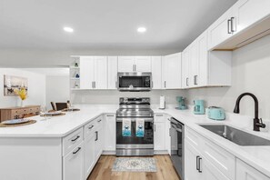 A modern kitchen with white cabinetry, stainless steel appliances, and a central island. - Peaceful Getaway~ Heated Pool ~10 Min to Beach (Largo)