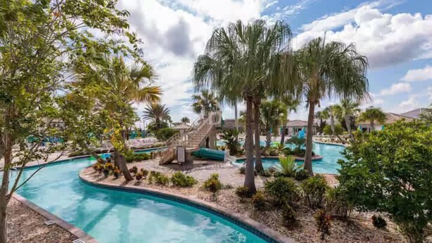 A pool area with palm trees, a water slide, and a staircase leading to a deck. - Cozy 6BR Home,Sleeps 16,Near Disney & Universal FL (Four Corners)