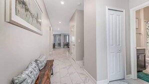 A hallway with a bench, a door, and a dining area in the background. - Cozy 6BR Home,Sleeps 16,Near Disney & Universal FL (Four Corners)