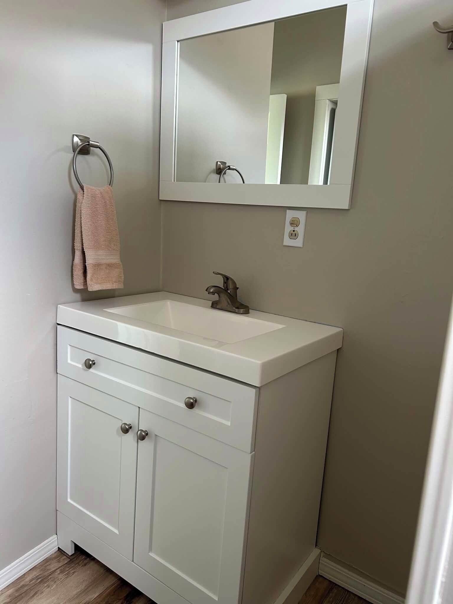 Une salle de bain avec un meuble-lavabo blanc, un miroir et un porte-serviettes.