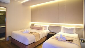 Habitación de hotel con dos camas, una mesita de noche y un aire acondicionado.
