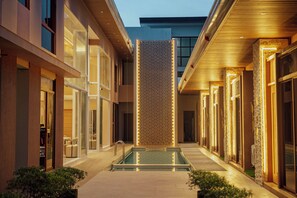 A modern hotel corridor with a central pool, glass doors, and a patterned wall. - Khami House Resort (Panglao)