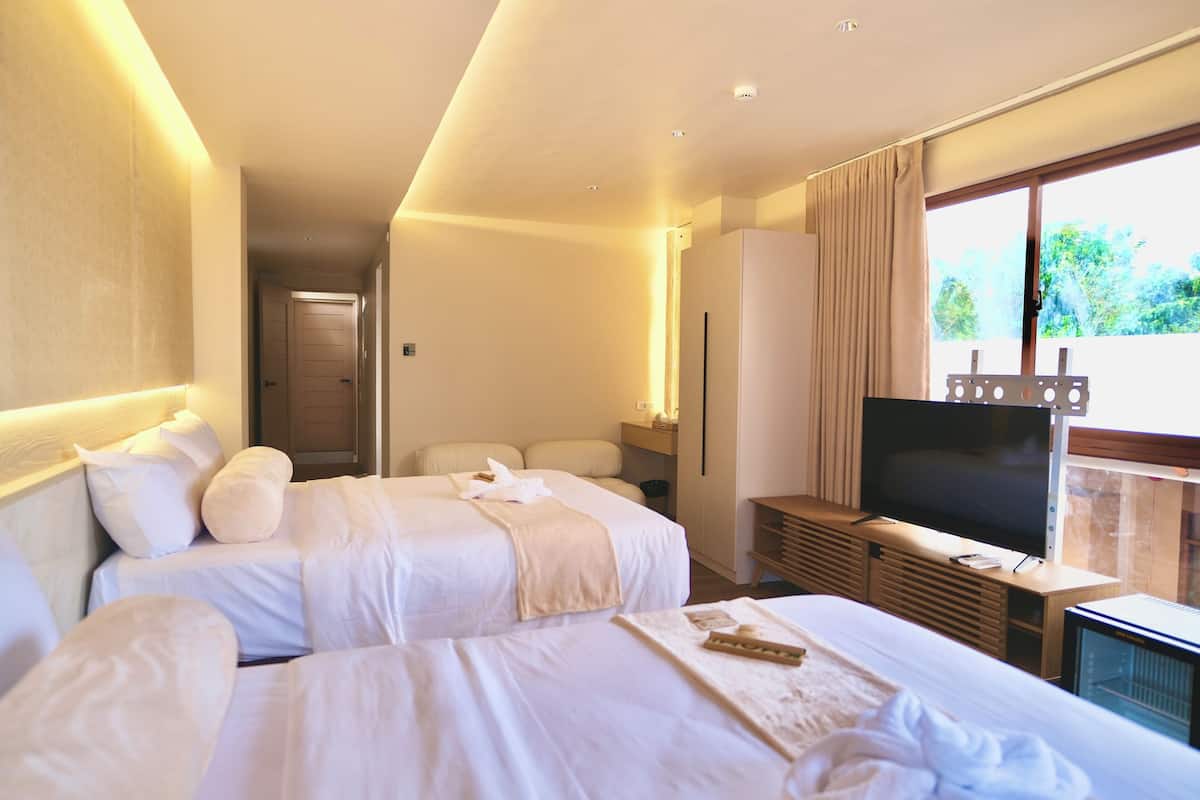 Et hotelværelse med to senge, et fjernsyn, minibar og et vindue med udsigt.
