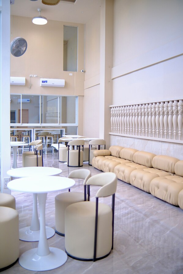 A spacious room with a large window, a sofa, and multiple tables and chairs. - Khami House Resort (Panglao)