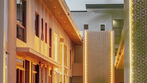 Un edificio moderno con un patio central, que presenta una pared con diseño y una fuente de agua reflectante.