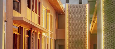 A modern building with a courtyard, featuring a patterned wall and a reflective water feature.