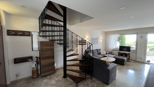 Ein modernes Wohnzimmer mit Wendeltreppe, Flachbildfernseher und Kamin.
