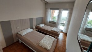 Ein Hotelzimmer mit zwei Einzelbetten, einem kleinen Tisch und einem Fenster mit Vorhängen.