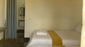A hotel room with two beds, a bathroom, and an air conditioning unit.