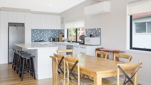 Une cuisine moderne avec des meubles blancs, un îlot central doté de tabourets et une table à manger avec des chaises.