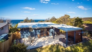 Une propriété résidentielle dotée d’un patio couvert, d’un espace salon extérieur et offrant une vue sur la mer.