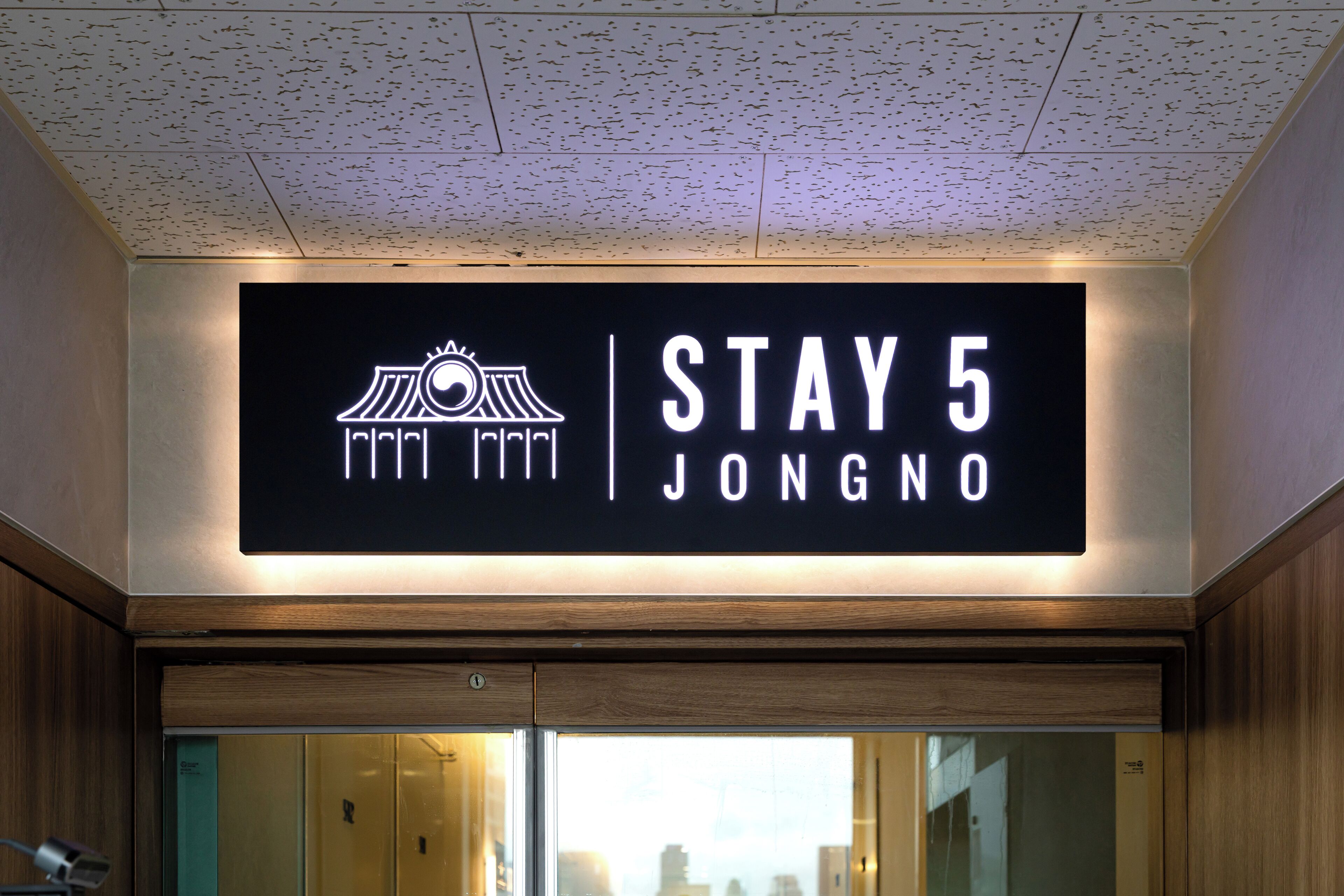 Placa de hotel com 'STAY 5 JONGNO' e um logotipo.