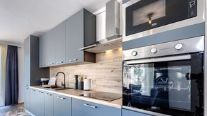 Eine moderne Küche mit grauen Schränken, einem eingebauten Backofen und einer Edelstahl-Dunstabzugshaube.