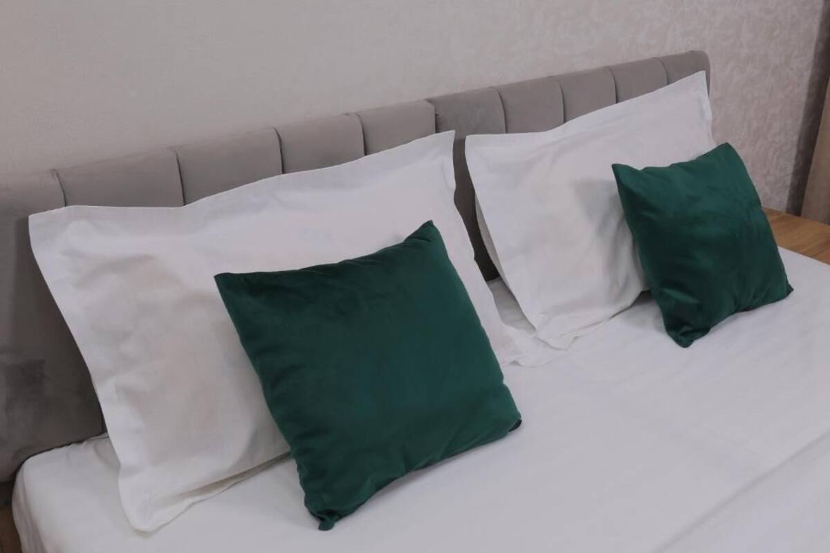 A bed with a grey upholstered headboard and white bedding.