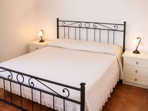 A single bed with a metal frame, white bedding, two bedside tables with lamps, and a white nightstand with drawers. - Casa della Campana nel centro di Portoferraio (Portoferraio)