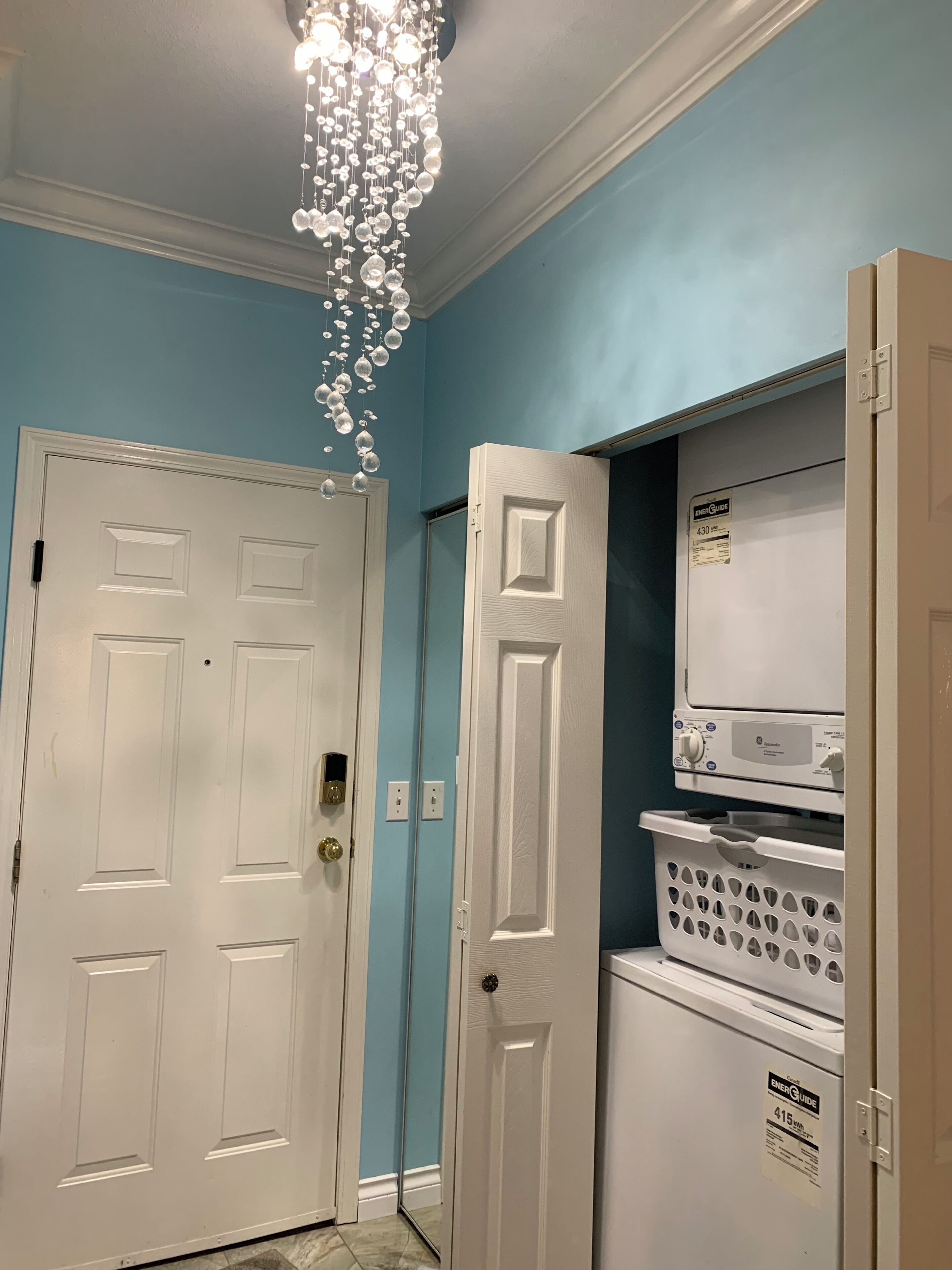 A hallway with a white door, a white door with a handle, a white appliance with a control panel, and a white appliance with a control panel.