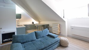 Un loft moderno con cocina, sofá y un techo inclinado único.