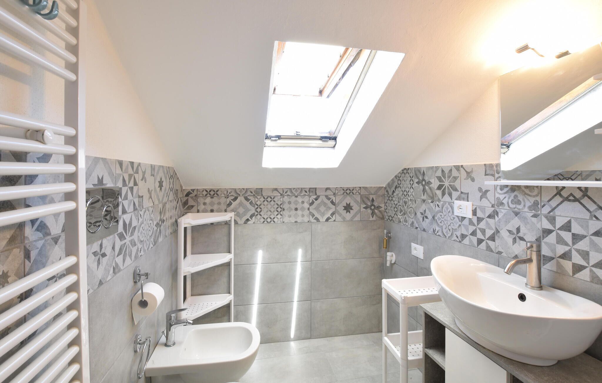 A bathroom with a skylight, a sink, a toilet, and a shower.