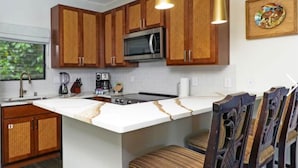 A kitchen with wooden cabinets, a stainless steel refrigerator, a microwave, and a white countertop.