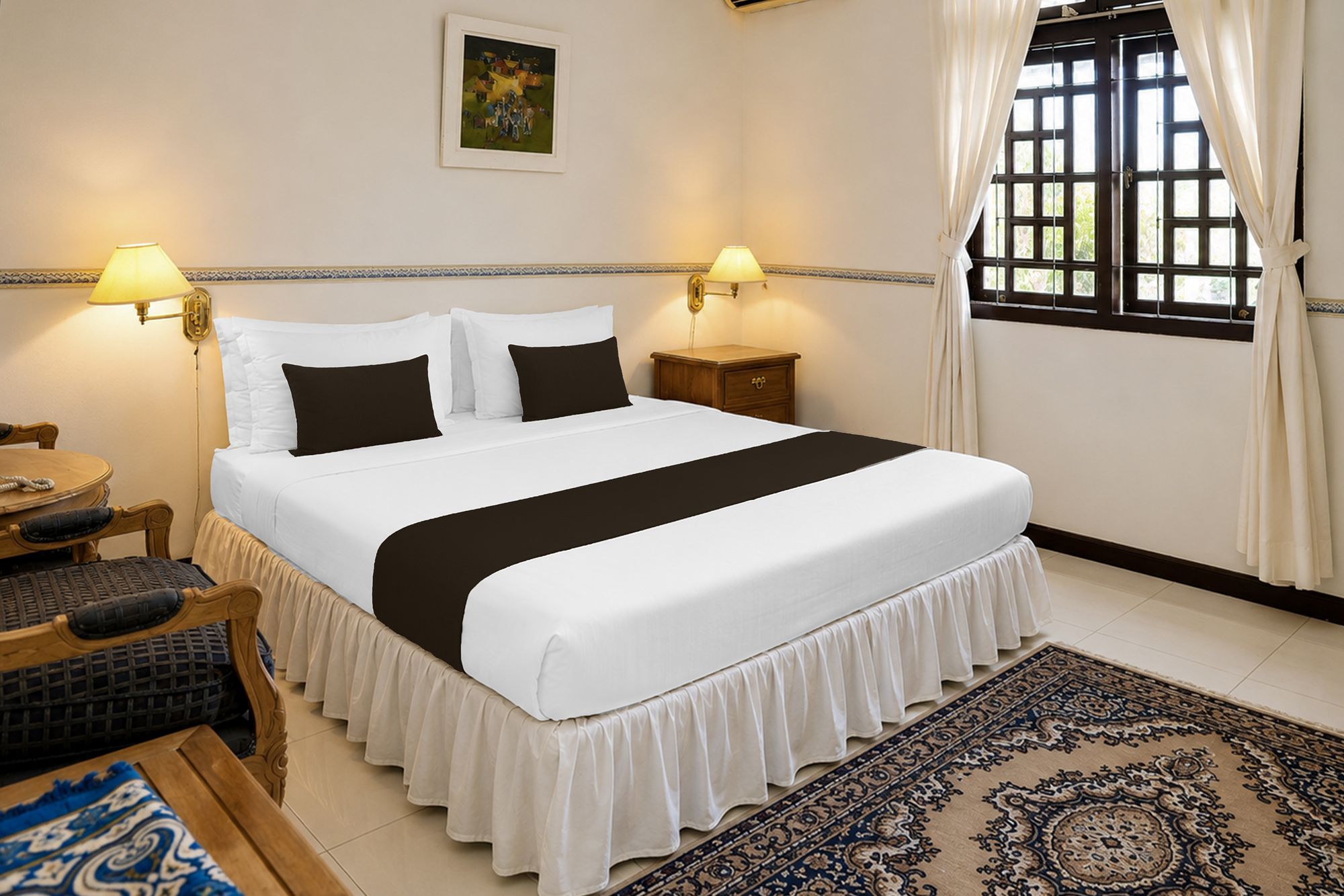 A neatly arranged hotel room with a bed, bedside lamps, a nightstand, a table with chairs, and a large window with curtains.