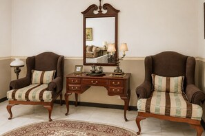 A room with two armchairs, a wooden side table, a mirror, and a patterned rug. - Hotel O near Pantai Padang formerly Bou (Padang)