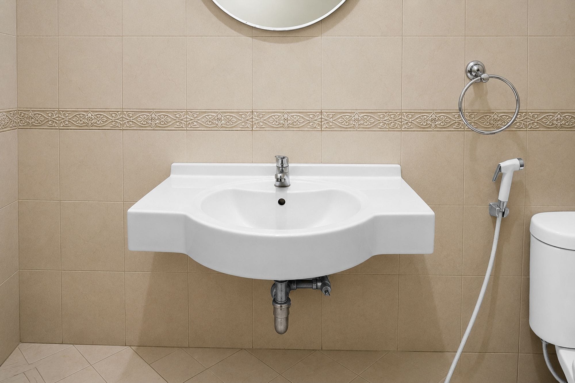 A bathroom with a white sink, a round mirror above it, and a toilet to the right.