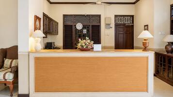 A reception area with a wooden reception desk, a clock, and a flower arrangement.