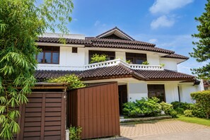 A two-story house with a tiled roof, a wooden gate, and a well-maintained garden. - Hotel O near Pantai Padang formerly Bou (Padang)