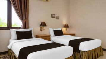 A hotel room with two beds, a window with curtains, an air conditioning unit, and two wall-mounted lamps.