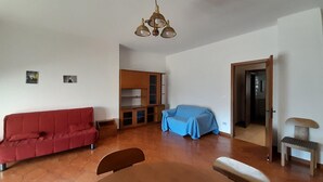 A living room with a red sofa, a blue covered chair, a wooden bench, a small table, and a ceiling light fixture. - Awesome apartment in Maglie with WiFi (Maglie)