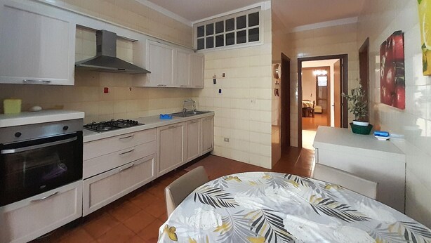 A compact kitchen with white cabinets, a stove, and a sink. There is a dining area with a table and chairs. - Awesome apartment in Maglie with WiFi (Maglie)