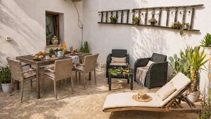A patio with a wooden table, wicker chairs, a lounge chair, and a wall-mounted plant shelf. - Cozy home in Militello in Val di Ca with WiFi (Militello in Val di Ca)