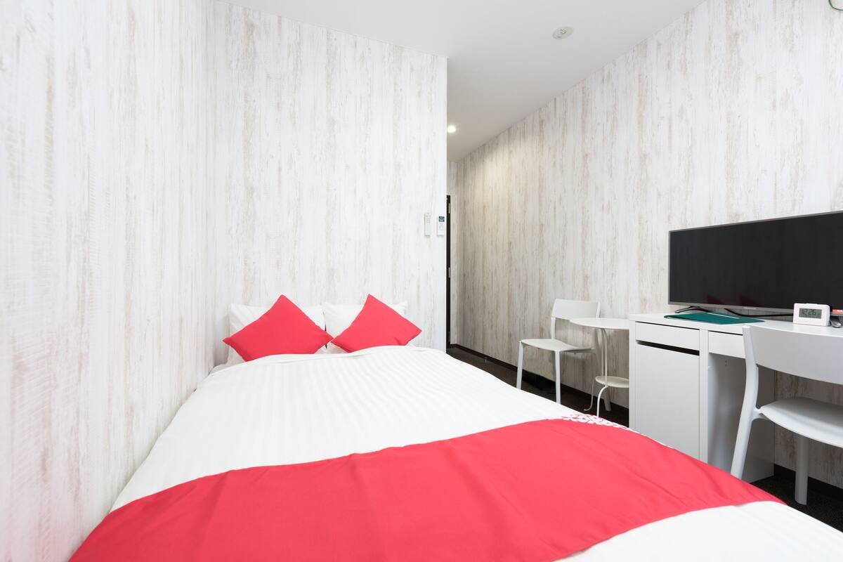 Habitación de hotel con cama, escritorio, silla y televisor.
