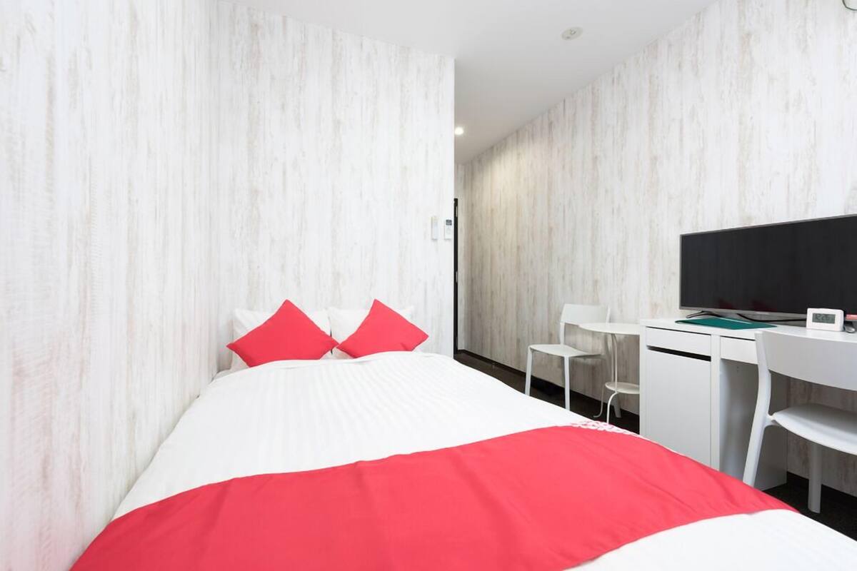 Una habitación de hotel con cama, escritorio, silla y televisión.