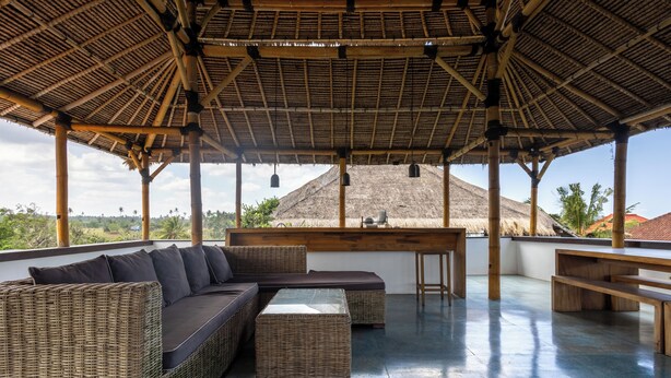 A covered outdoor seating area with wicker furniture and a bar.
