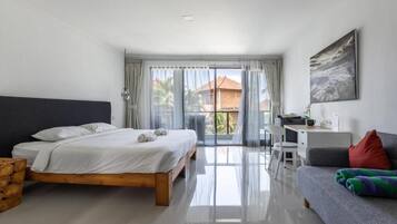 A bedroom with a bed, a desk, a sofa, and a balcony with curtains.