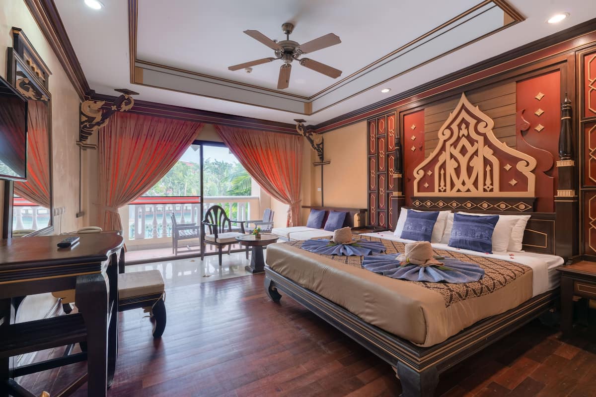 A hotel room with a large bed, a desk, and a balcony.