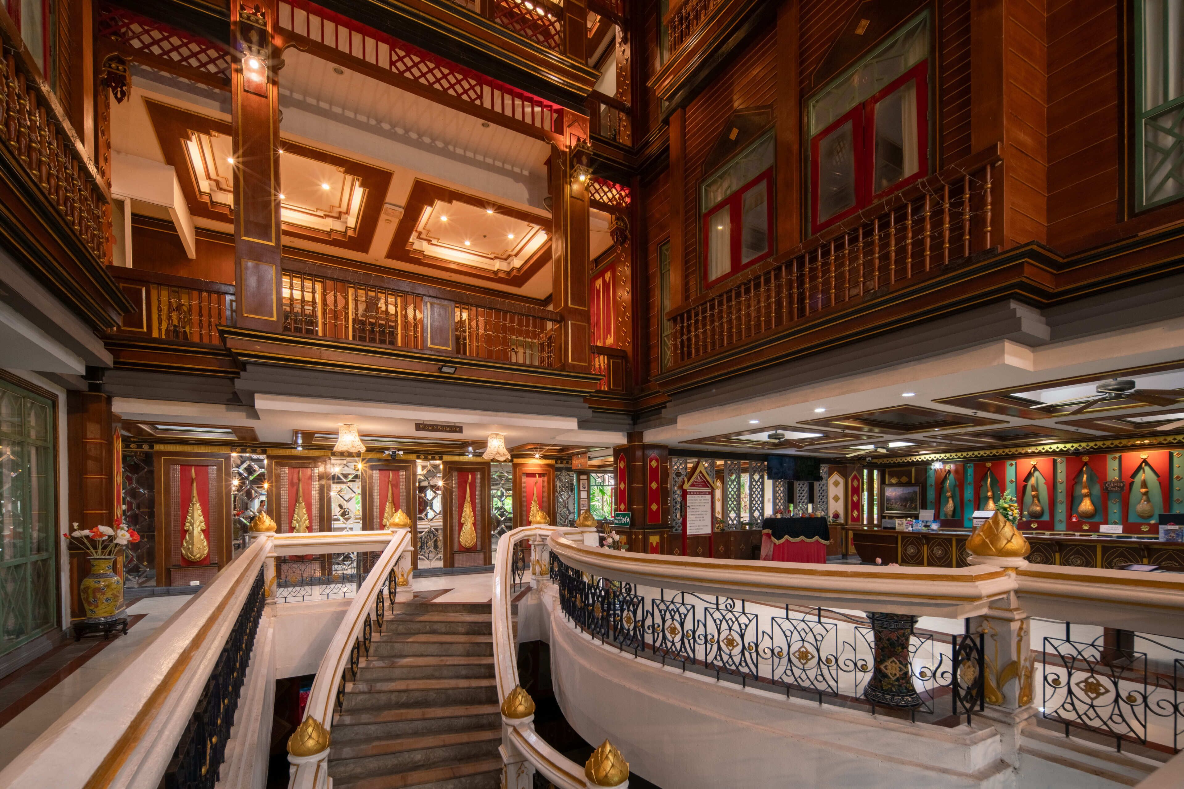 A grand interior with a staircase, ornate railings, and a reception area.