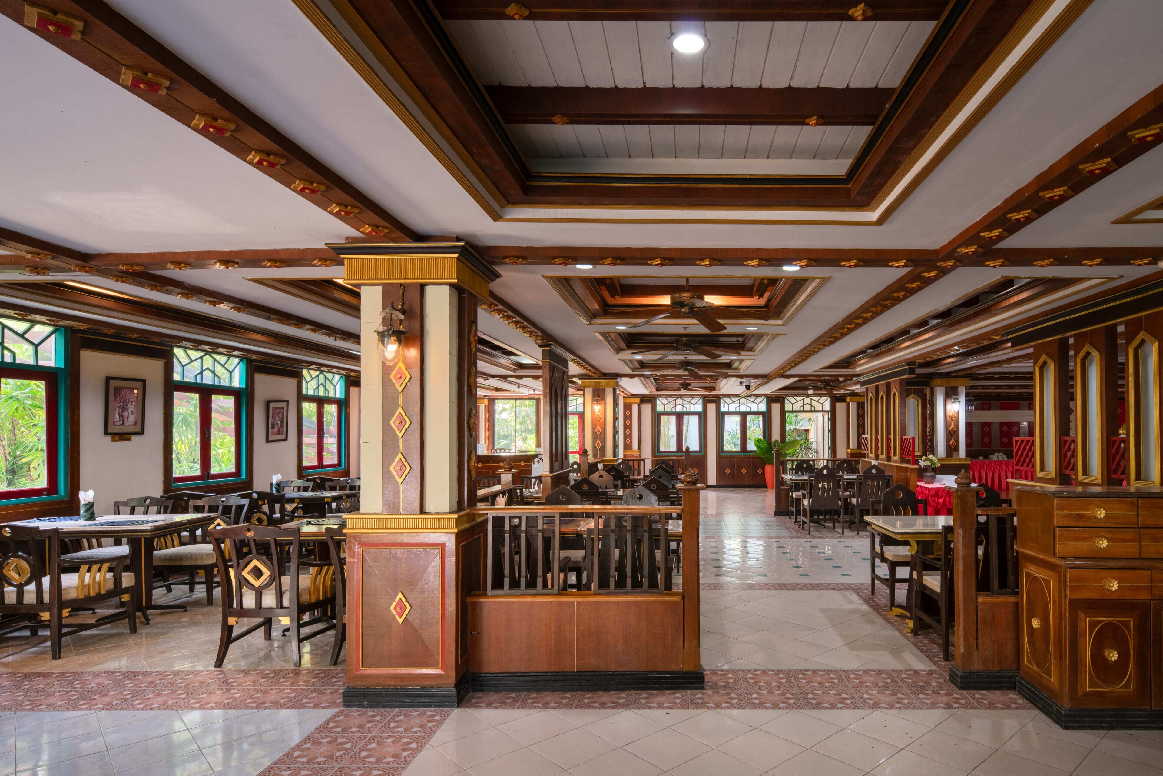 Un restaurante espacioso con mobiliario de madera, una columna central y amplias ventanas.