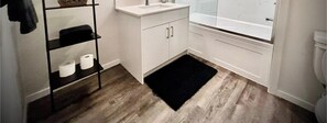Een badkamer met een wit wastafel, een toilet en een zwart tapijt op de vloer.