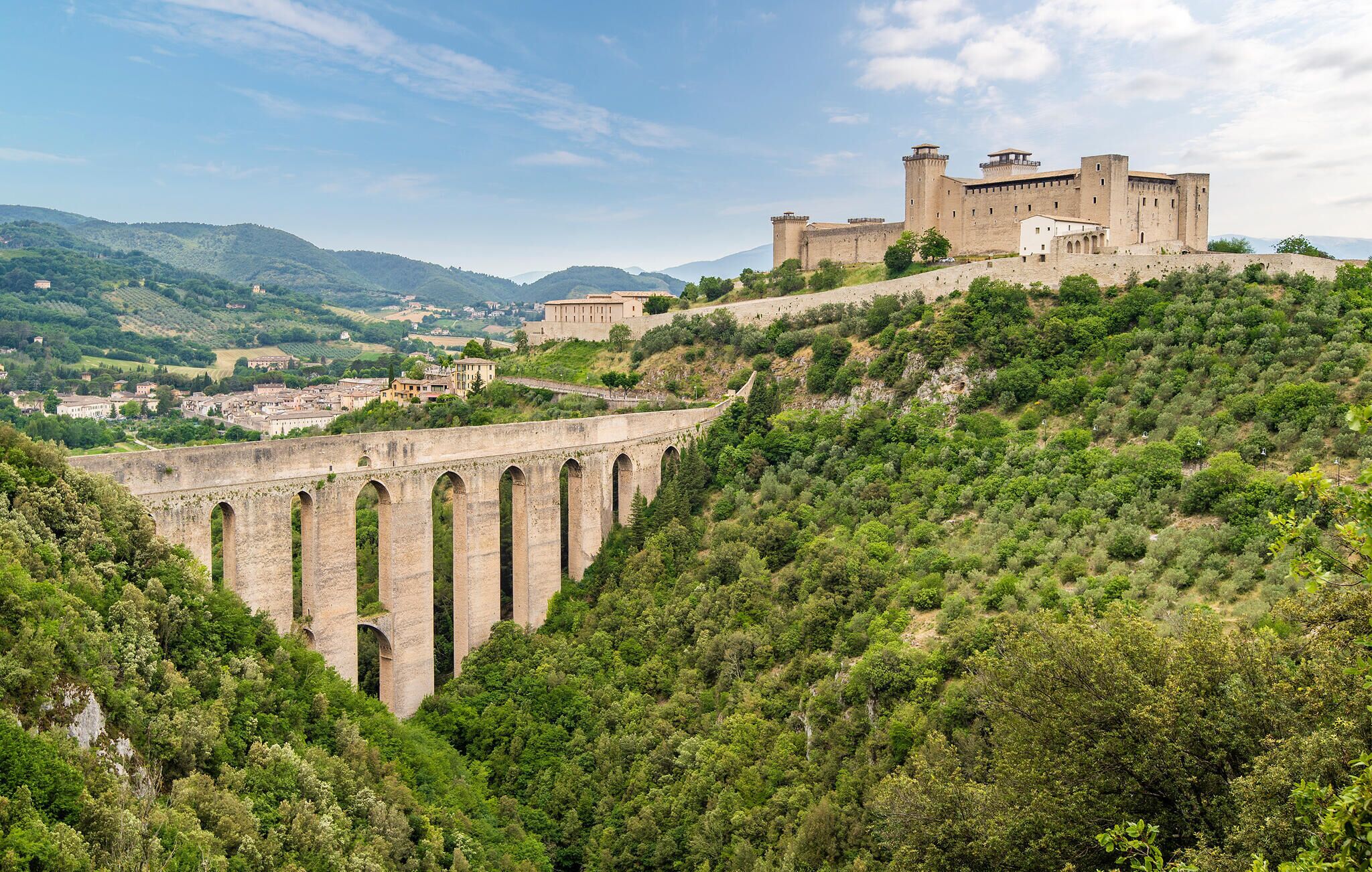 Un castillo histórico en una colina con un puente de piedra al frente.