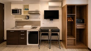 A compact kitchen with a microwave, stove, sink, and a flat-screen TV. - Suk41 (Bangkok)