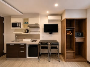Cocina compacta con microondas, estufa, fregadero y televisor de pantalla plana.