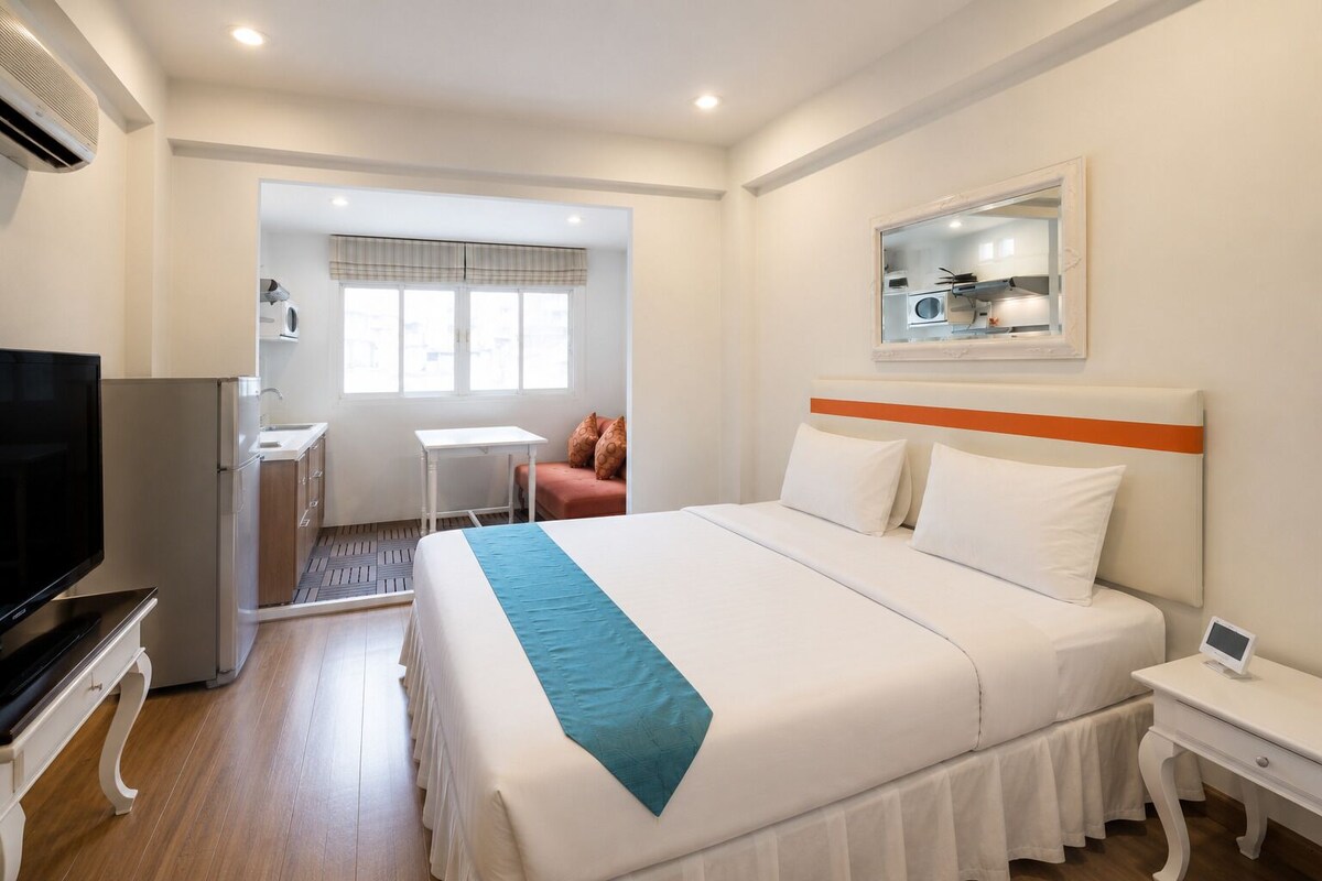 A hotel room with a bed, a TV, a desk, a chair, and a window.