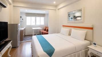 Ein Hotelzimmer mit Bett, Fernseher, Schreibtisch, Stuhl und Fenster.