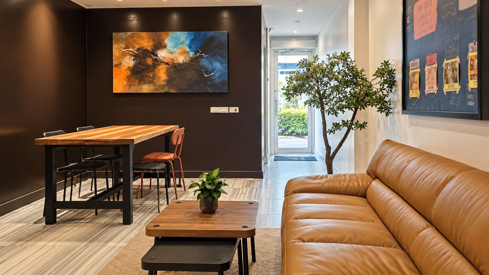 Ein modernes Interieur mit einem Ledersofa, einem Holzesstisch und einem großen abstrakten Gemälde.