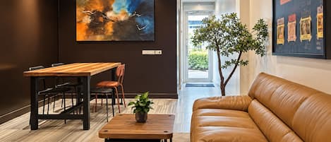 A modern interior with a leather sofa, a wooden dining table, and a large abstract painting.