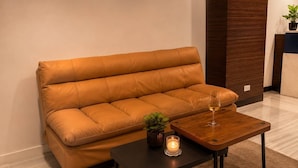 A modern living room with a leather sofa, a wooden coffee table, a small potted plant, and a candle. - Suk41 (Bangkok)