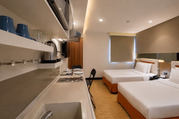 Habitación de hotel con kitchenette, dos camas, una ventana y un televisor.