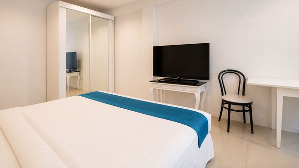 A hotel room with a bed, a desk with a TV, and a chair. - Suk41 (Bangkok)
